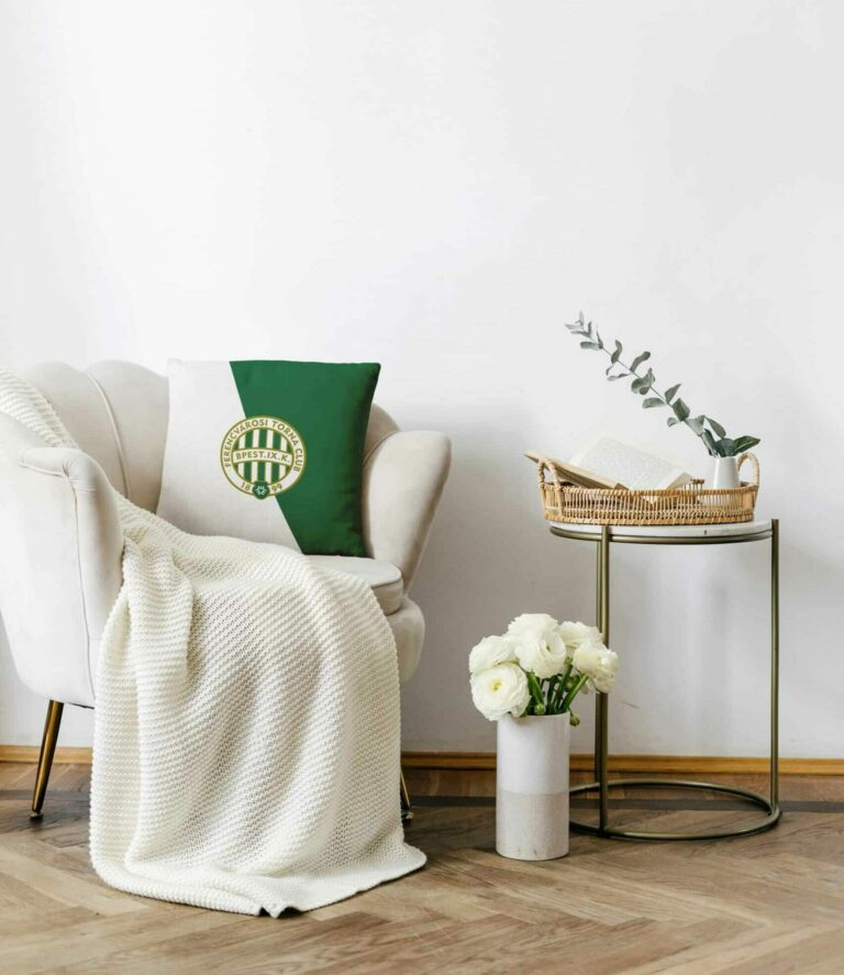 Elegant living room with classic design. Apartment interior with white textiled armchair in art deco style standing close to side table with home decor. Objects against white copy space wall
